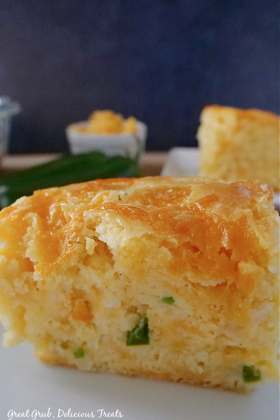 A close up photo of a piece of cornbread where you can see the diced jalapeno and onion, and the cheese baked on top. 