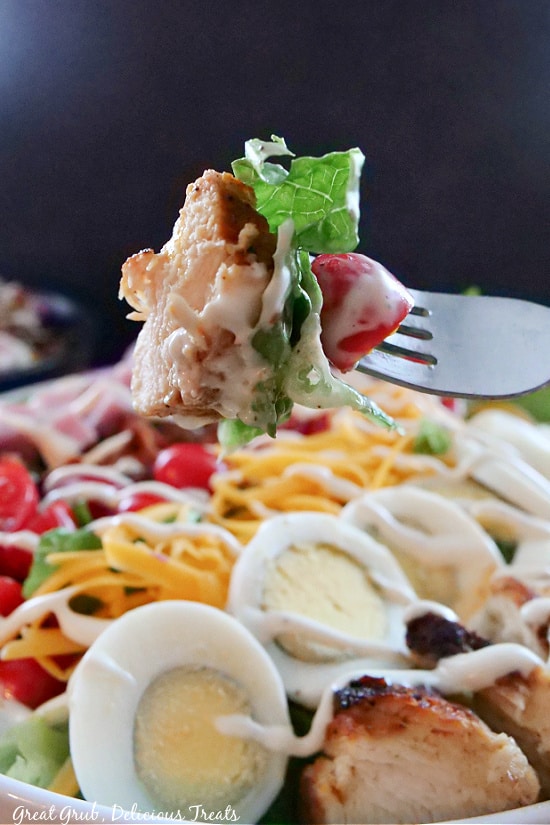 A giant bite of salad on a fork, covered in ranch dressing. 