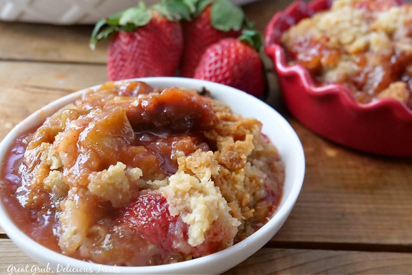A small white bowl and a small red bowl filled with strawberry rhubarb crisp.