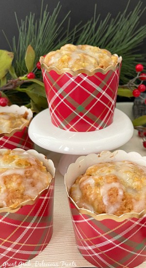 A muffin in a red plaid liner, topped with vanilla glaze.