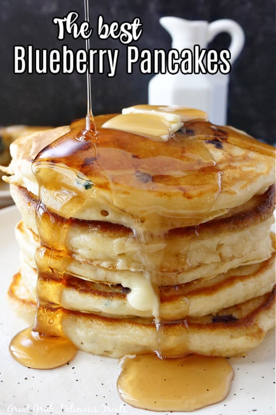 A stack of five pancakes topped with butter and maple syrup.