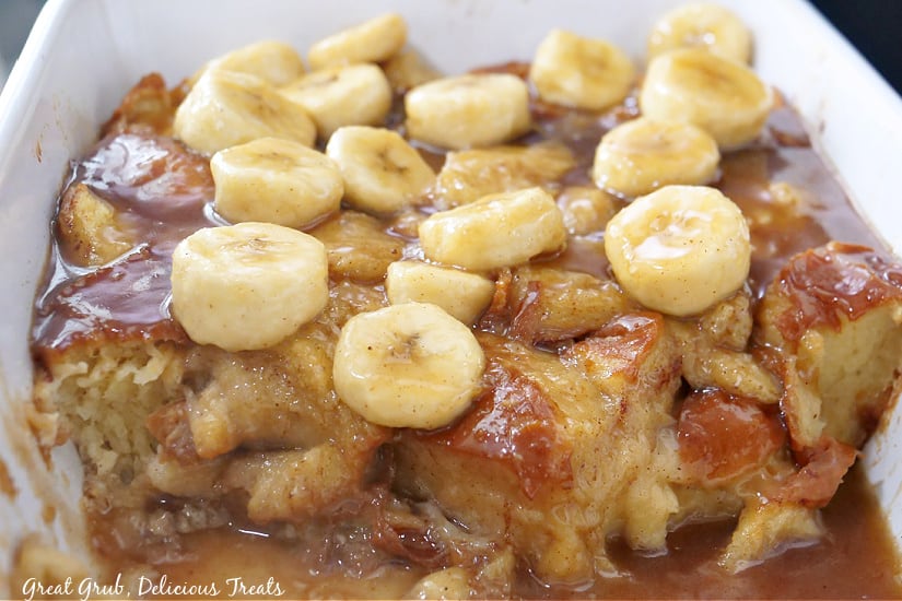 A white baking dish filled with bread pudding and sliced bananas on top.