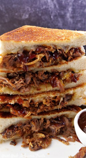 A close-up picture of brisket grilled cheese sandwiches cut in half and stacked on top of each other. 