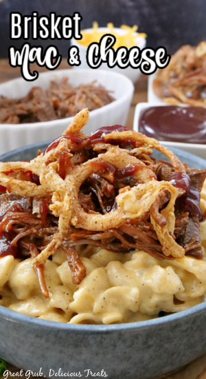 A large bowl of mac and cheese, topped with brisket, barbecue sauce, and onion strings. 
