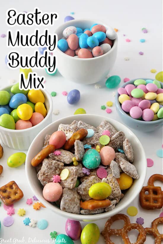 A white bowl filled with Easter Muddy Buddy Mix and three other white bowls filled with pastel chocolate candies.