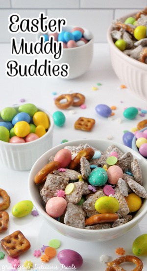White bowls filled with Easter puppy chow mix with candies and pretzels laying around the bowls.