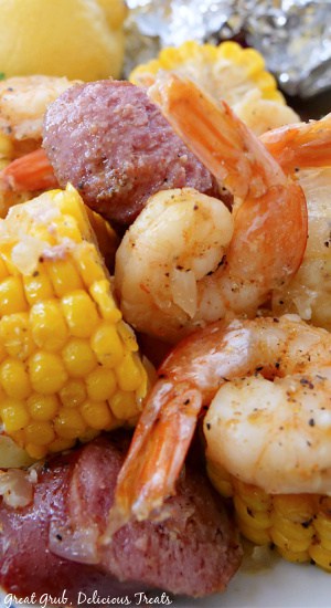 A close up of corn, sausage, shrimp and potatoes in a foil packet.
