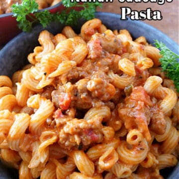 A blue bowl filled with pasta and Italian sausage.