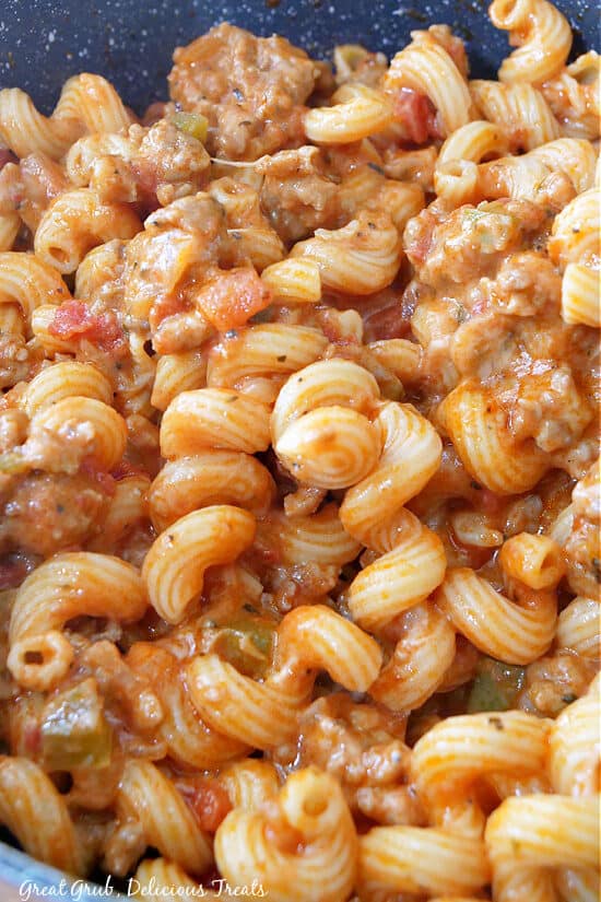A close up of pasta in a pan after being mixed with sausage.