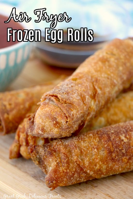 Four golden brown egg rolls on a wood surfact.
