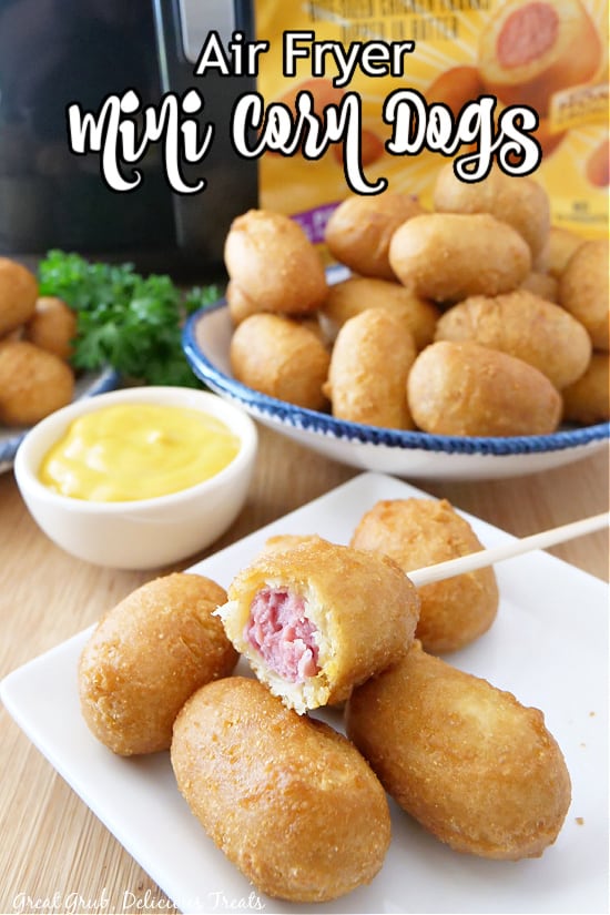 Two plates filled with mini corn dogs, with a small bowl of mustard in the background.