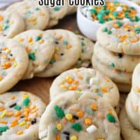 A wood surface with over a dozen dinosaur sugar cookies on it.