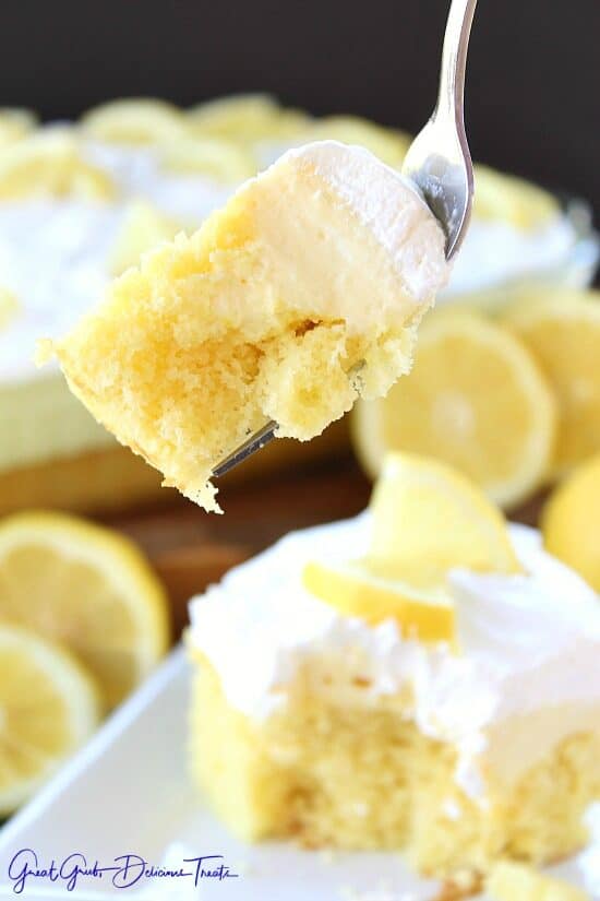 A close up of a bite of lemon poke cake on a fork.