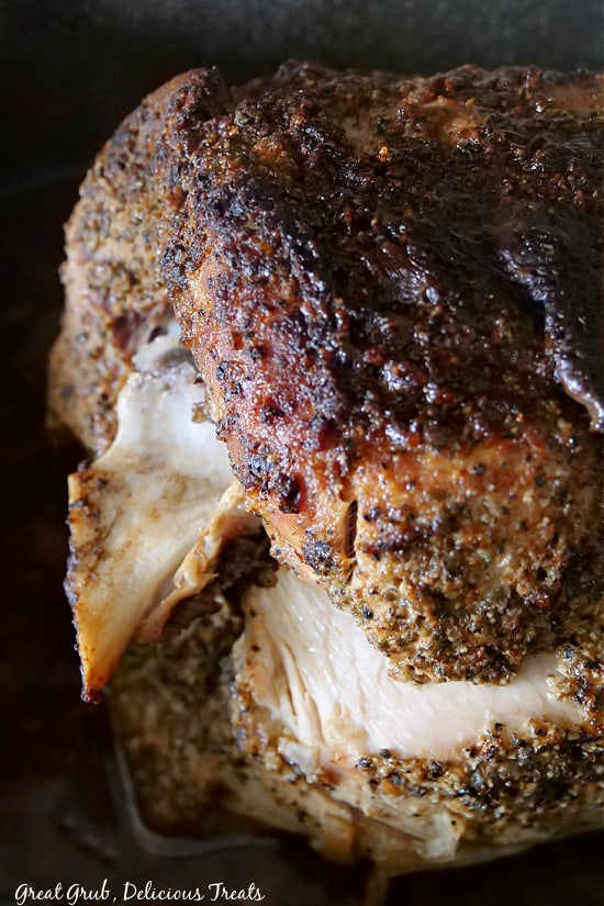 A pork shoulder roast that was just pulled out of the oven, showing all the seasoning on the outside and the golden brown outside of the roast.