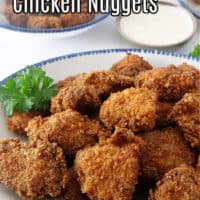 A close up picture of a blue trimmed white plate filled with spicy chicken nuggets.