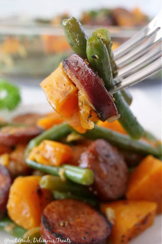 A bite of vegetables and sausage on a fork.