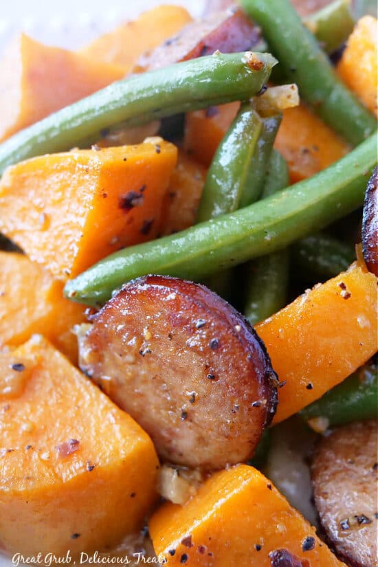 A super close up of sweet potatoes, green beans and sliced sausage.
