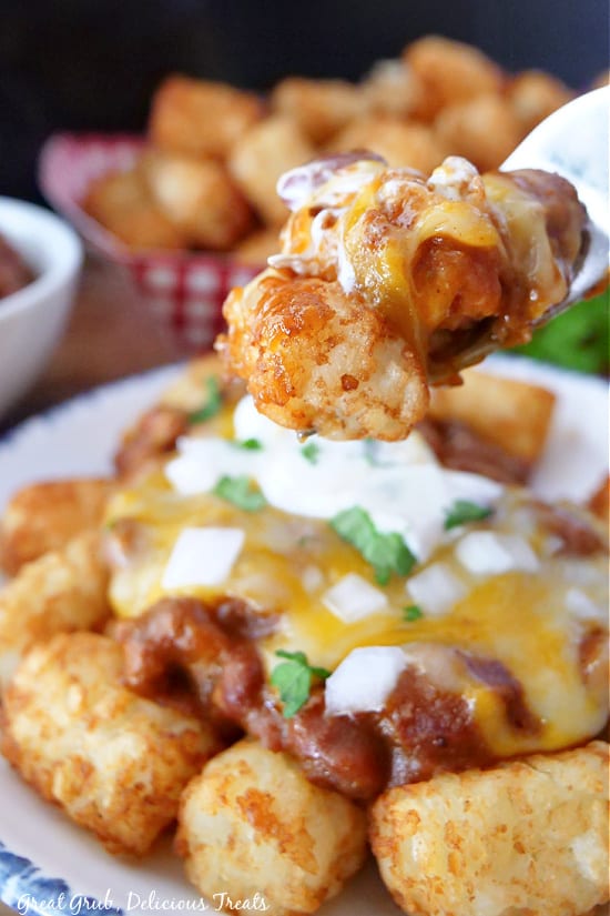 A bite of chili cheese tots on a spoon.