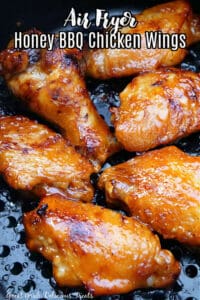 An air fryer tray filled with chicken wings that are coated in Honey BBQ sauce.