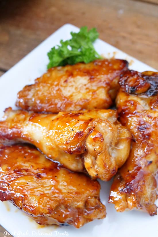 A close up photo of honey BBQ chicken wings on a square white plate.