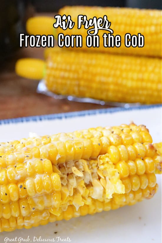 A close up photo of a white plate with an air fried ear of corn with a bite taken out of it and 3 more ears of corn in the background.