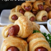 Two plates with pigs in a blanket stacked up on top of them.