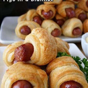 Two plates with pigs in a blanket stacked up on top of them.