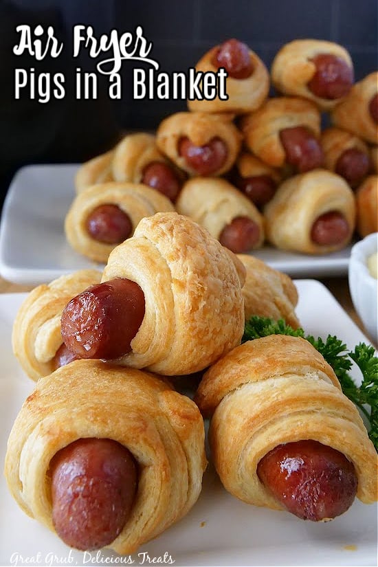 Two white plates with pigs in a blanket stacked up on top of one another.