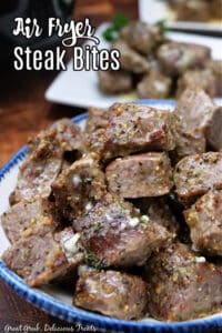 A white bowl with blue trim that is filled with seasoned steak bites.