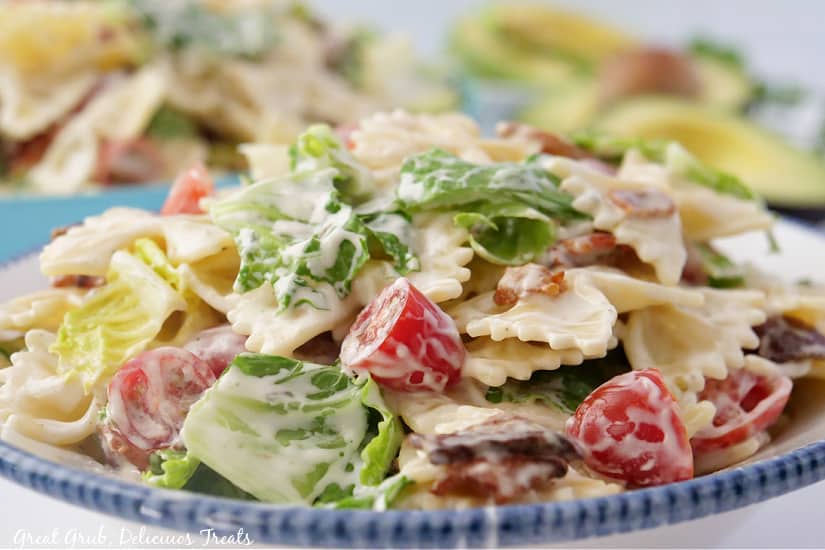 A large white bowl with blue trim on the edges filled with BLT pasta salad tossed in ranch dressing.