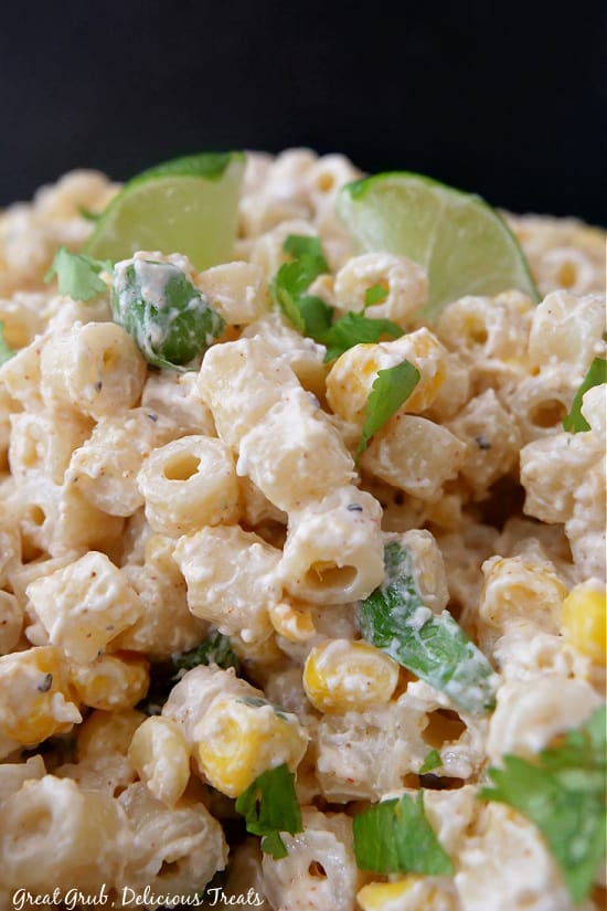 A close up photo showing noodles, corn, and cilantro all covered in street corn dressing.