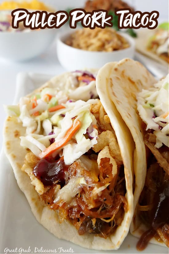 Two tacos laying on a white plate topped with cabbage.