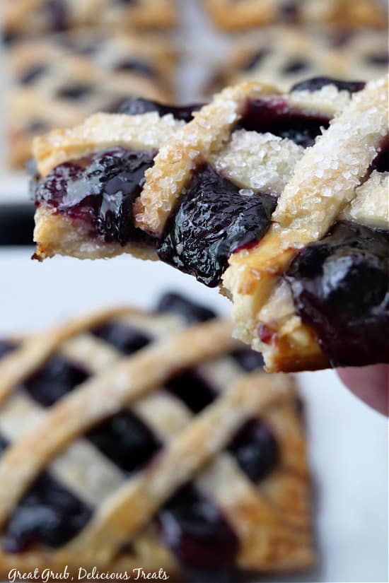 A super close up photo of a blueberry pastry showing a bite taken out of it and the delicious coarse sugar that is on top.