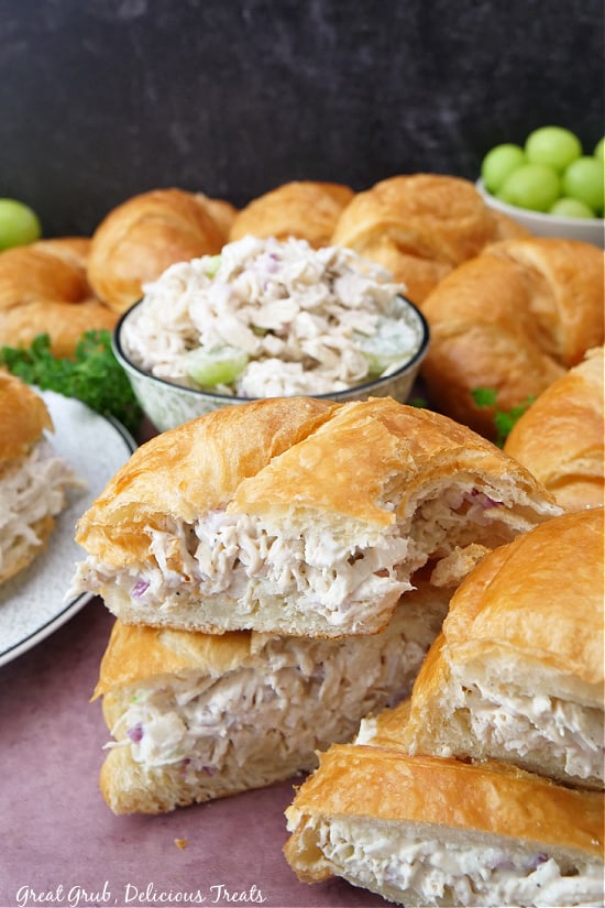 Croissant sandwiches filled with chicken salad, cut in half, and stacked up on each other.
