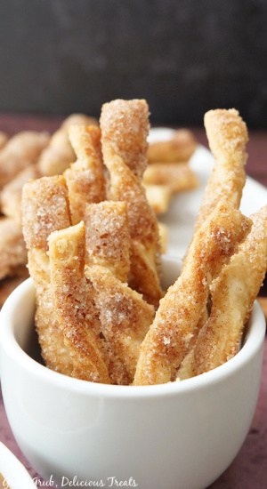 Cinnamon Twists sitting upright in a white container with more cinnamon twists in the background.