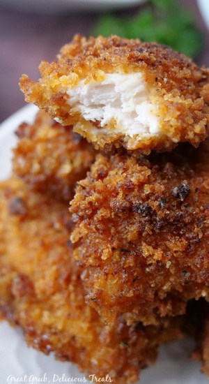 Close up of a stack of crispy chicken bites with a bite taken out of one of them.