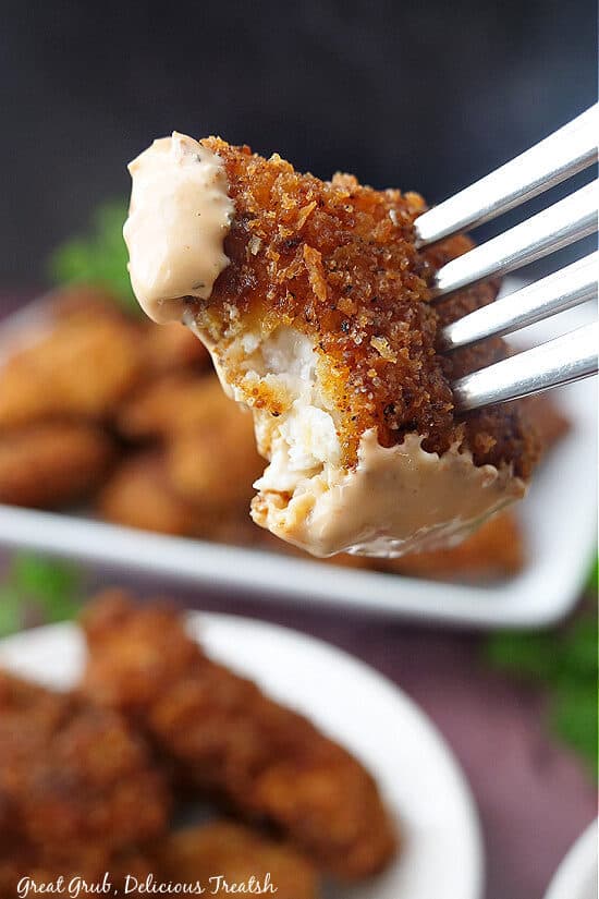 A close up of a fried chicken bite with a bite taken out of it.