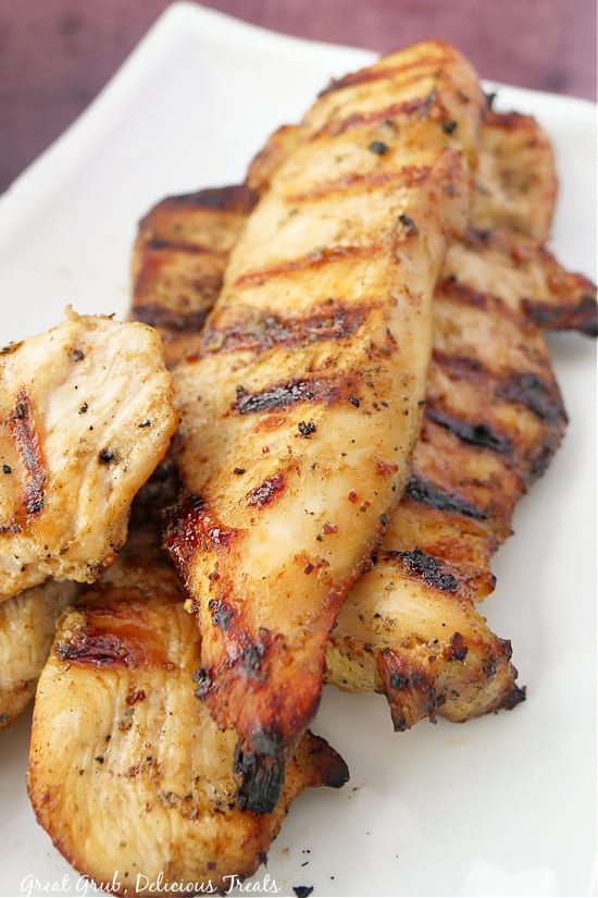 Freshly barbecued and sliced chicken breasts on a white plate.