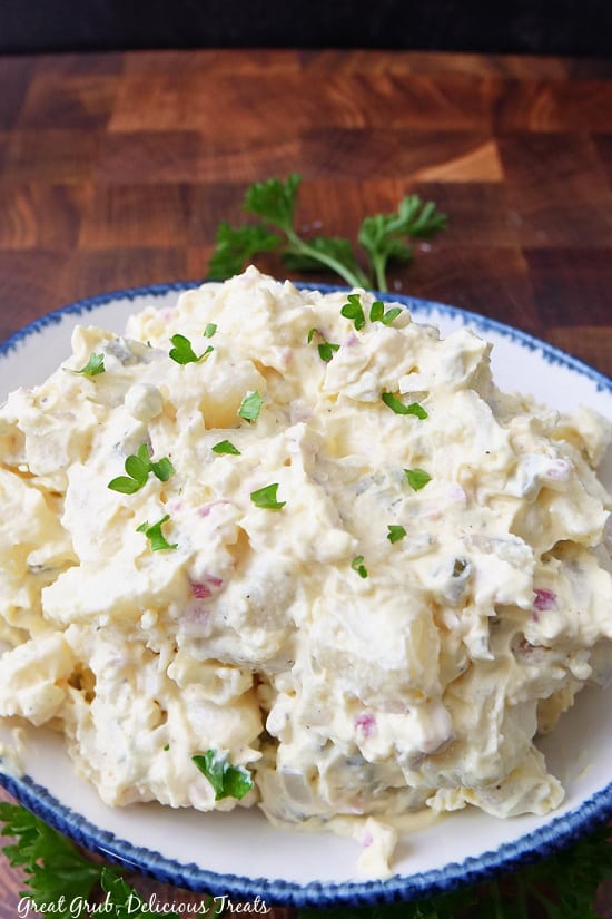 A plate loaded with a serving of potato salad with chopped parsley on top.