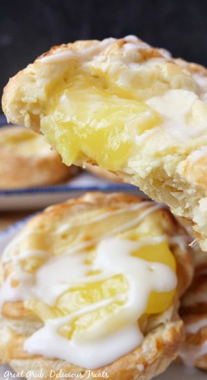Two lemon pastries with one being held in front of the camera with a couple bites taken out of it.