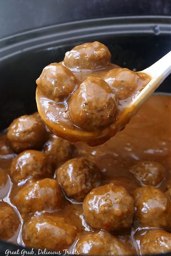 A large ladle of meatballs with gravy.