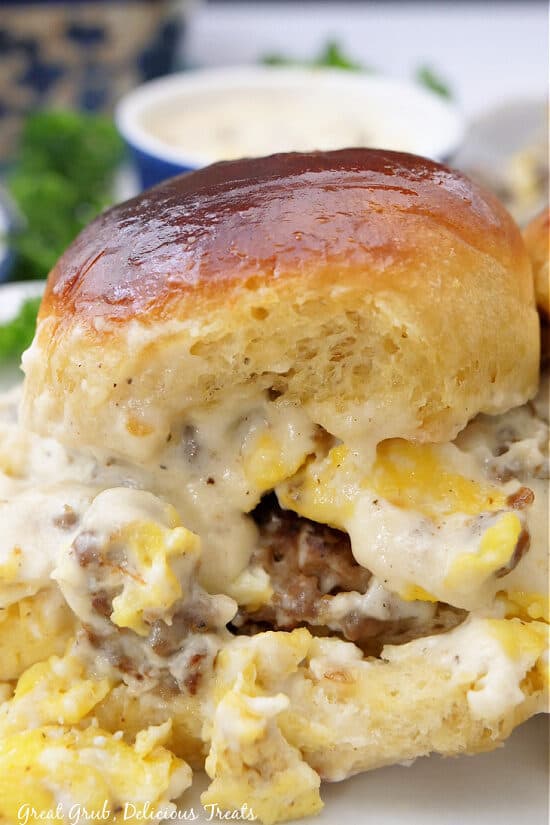 A close up photo of a breakfast slider that is loaded with eggs, sausage, and gravy.
