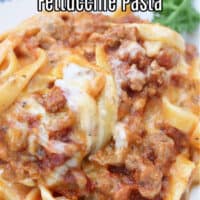 Fettuccine alfredo on a plate with a mix of meat sauce and alfredo sauce.