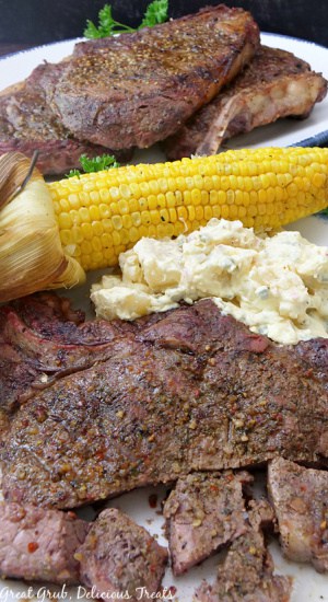 A plate full of steak and a seasoned corn on the cob.