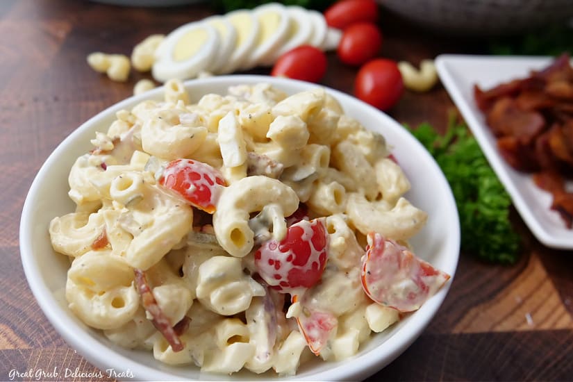 A small white bowl filled with a serving of bacon pasta salad.