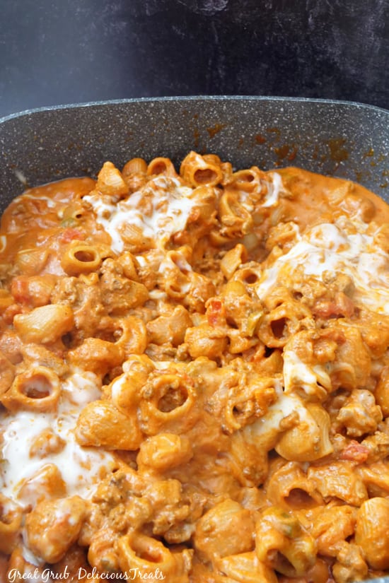 An overhead shot of creamy ground beef pasta in a large pot, covered with mozzarella cheese.