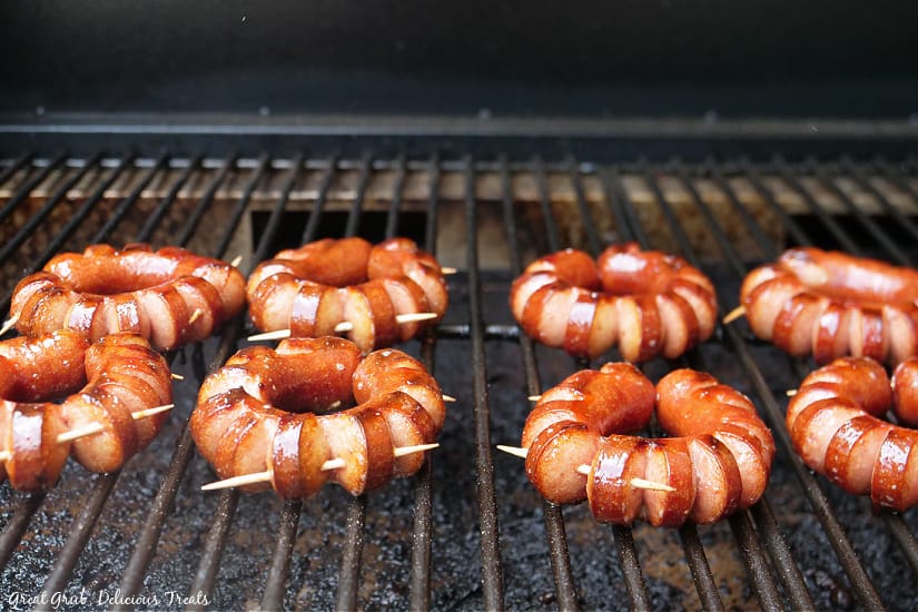 Eight hot dogs on the grill with are cut and made in circles, held together with toothpicks and grilled.