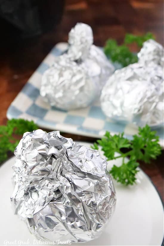 Three bulbs of garlic wrap up in aluminum foil after being air fried.
