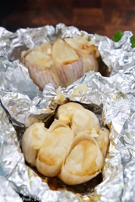 Two bulbs of garlic wrapped in foil and opened after being cooked in the air fryer.