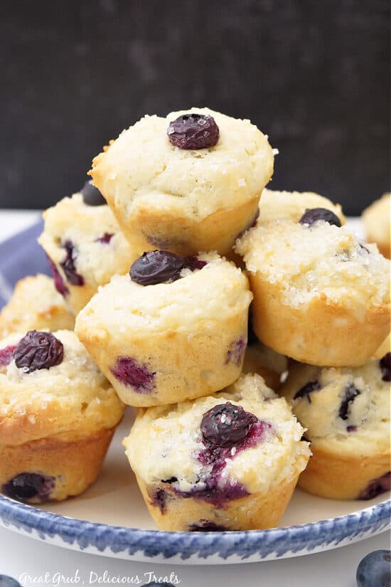 A stack of blueberry mini muffins on a white plate with blue trim.